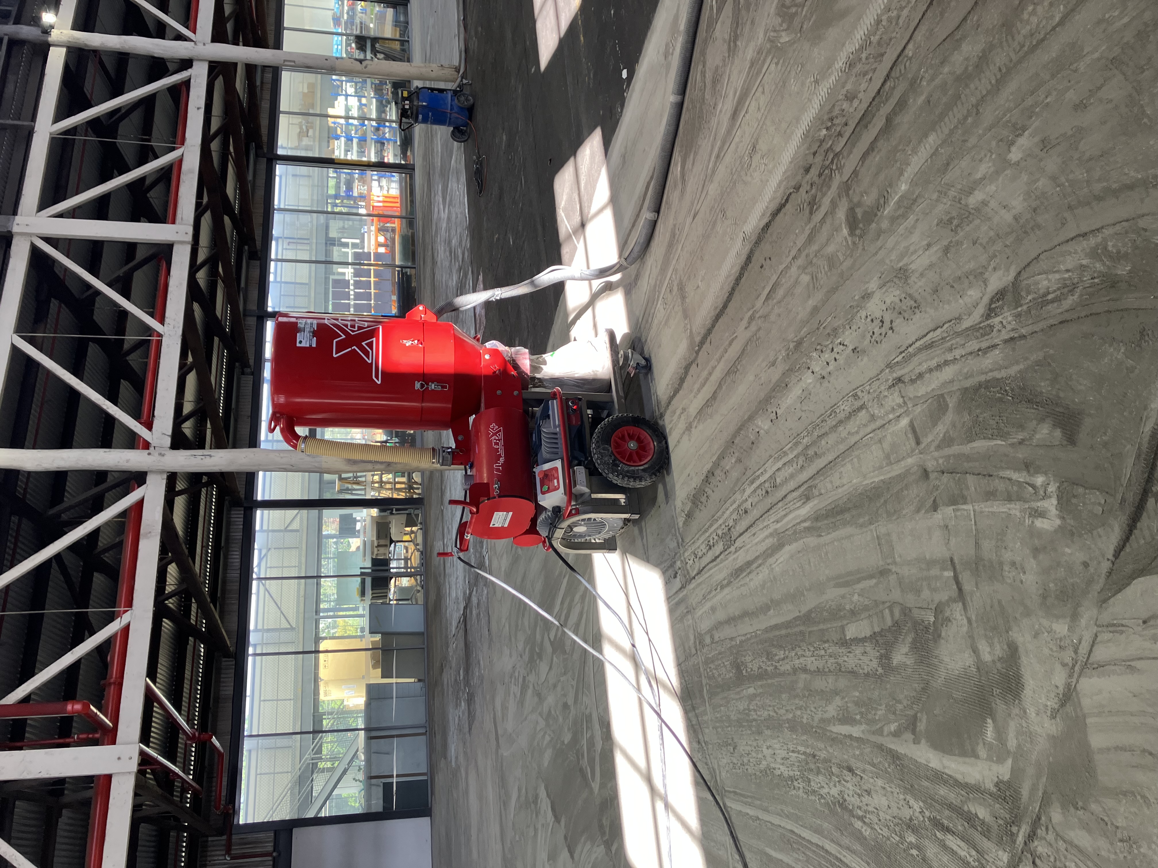 Surface preparation crew treating concrete floor along embedded rails in historic warehouse before new coating installation